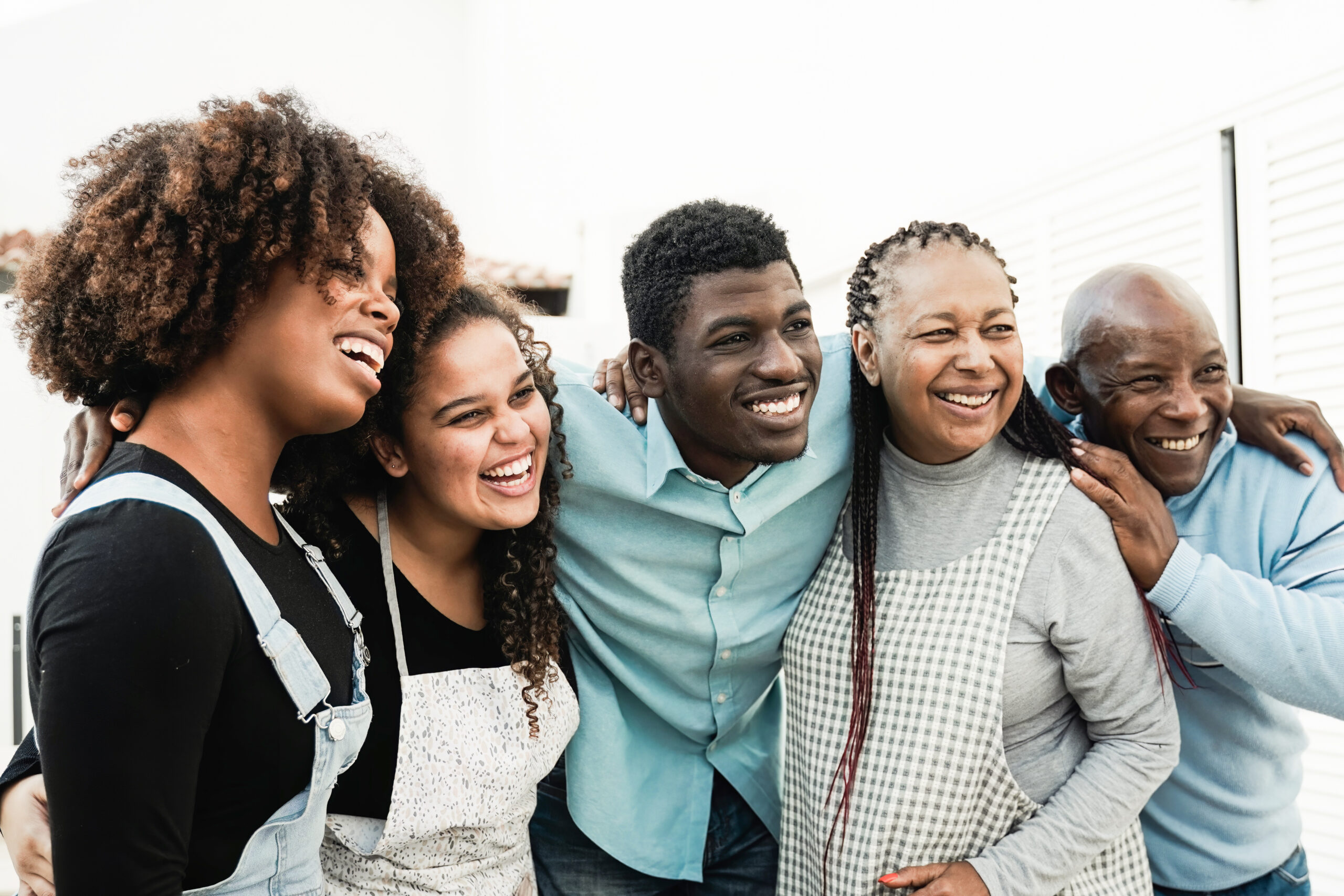 African family having fun hugging together. Happy Father, mother, daughters, brother making healthy food dinner outdoors